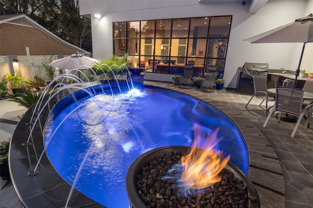 view of swimming pool featuring a fire pit, a patio, a hot tub, and pool water feature