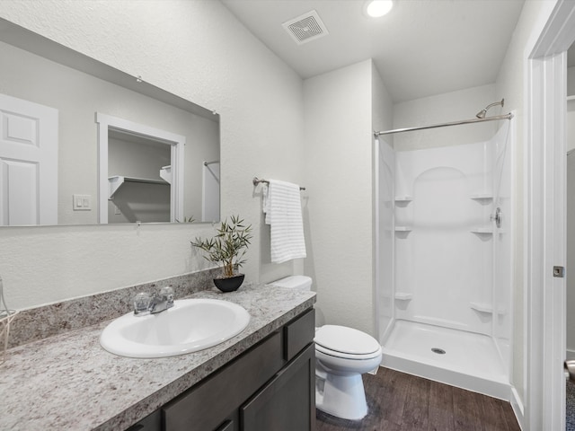 bathroom with walk in shower, vanity, toilet, and hardwood / wood-style flooring