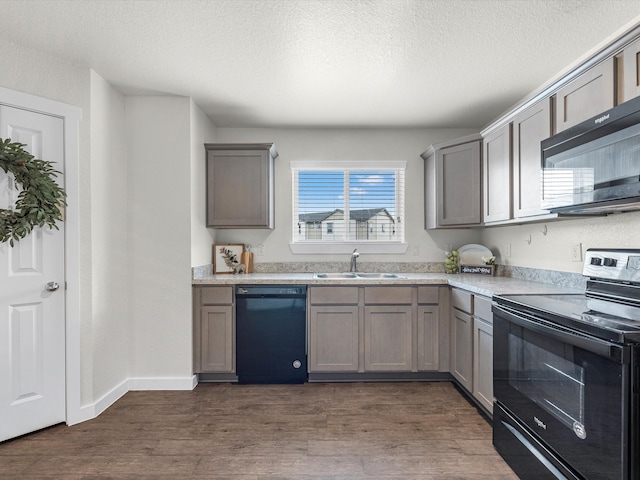 kitchen featuring black appliances, a textured ceiling, dark wood-type flooring, and sink