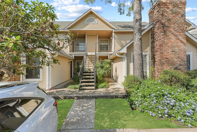 view of front of home featuring a balcony and a front lawn