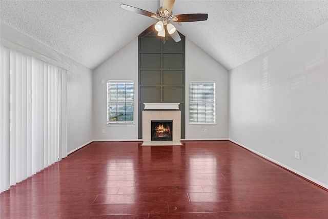 unfurnished living room with vaulted ceiling, a fireplace, a textured ceiling, wood-type flooring, and ceiling fan