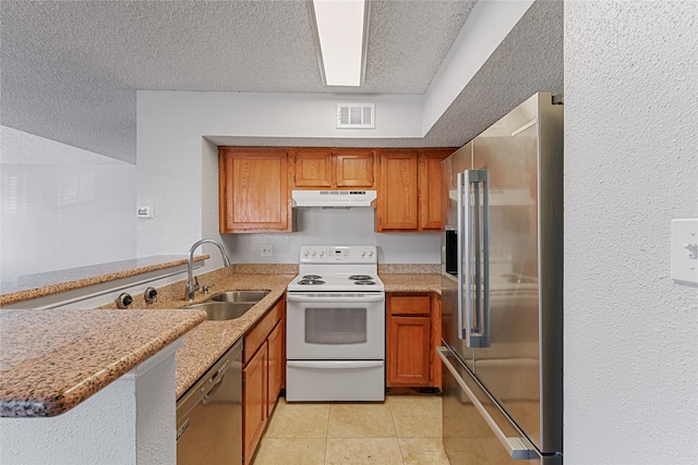 kitchen with light stone counters, kitchen peninsula, stainless steel appliances, a textured ceiling, and sink