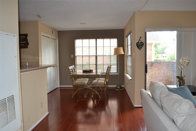 dining area with a textured ceiling and dark wood-type flooring