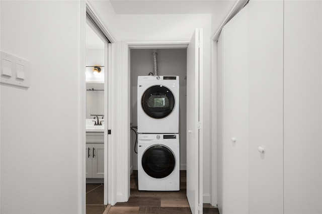 laundry room featuring stacked washer / dryer, sink, and dark wood-type flooring