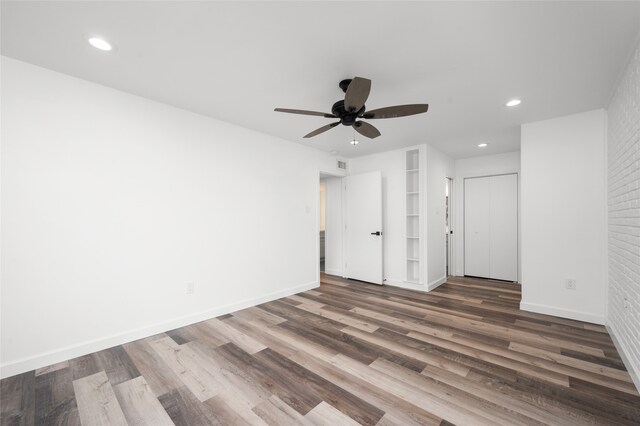 empty room with ceiling fan, dark wood-type flooring, and brick wall