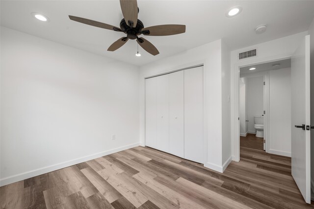 unfurnished bedroom featuring ceiling fan, light hardwood / wood-style flooring, and a closet