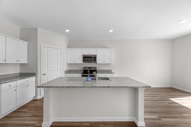 kitchen featuring hardwood / wood-style flooring, stainless steel appliances, a center island with sink, and white cabinets