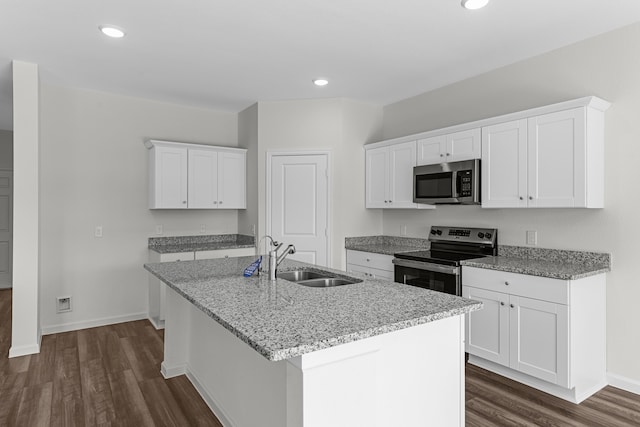 kitchen featuring appliances with stainless steel finishes, dark wood-type flooring, white cabinets, and a center island with sink