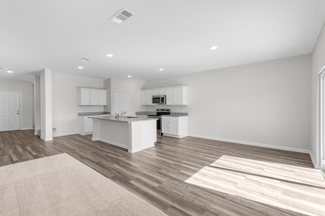 kitchen featuring an island with sink, light hardwood / wood-style flooring, stainless steel appliances, sink, and white cabinets