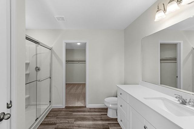 bathroom with vanity, hardwood / wood-style flooring, a shower with shower door, and toilet