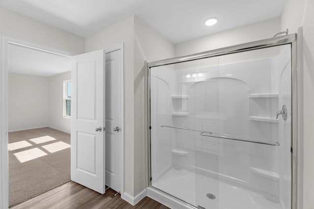 bathroom with hardwood / wood-style floors and a shower with shower door