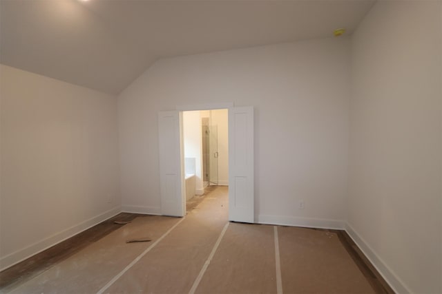 empty room featuring lofted ceiling and baseboards