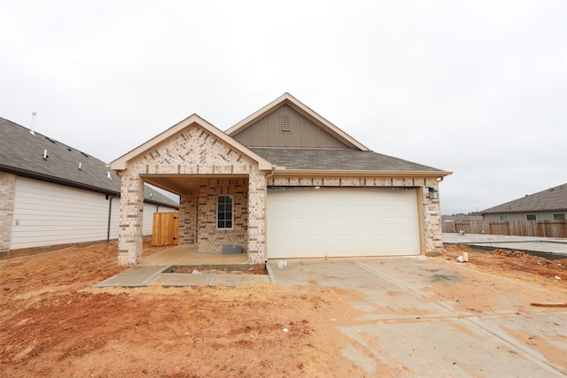 view of front of property featuring driveway, an attached garage, board and batten siding, and brick siding