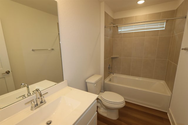 bathroom with washtub / shower combination, toilet, vanity, and wood finished floors