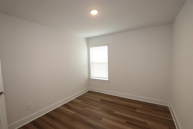 unfurnished room with baseboards and dark wood-style flooring