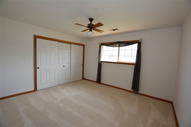 unfurnished bedroom featuring ceiling fan, light colored carpet, and a closet