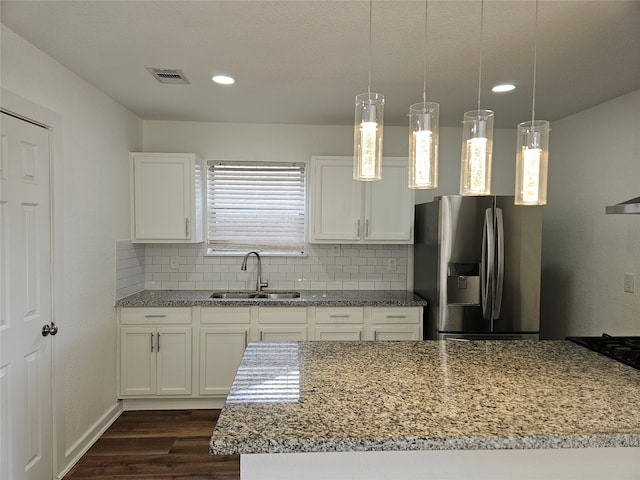 kitchen with a wealth of natural light, sink, white cabinets, stainless steel refrigerator with ice dispenser, and hanging light fixtures