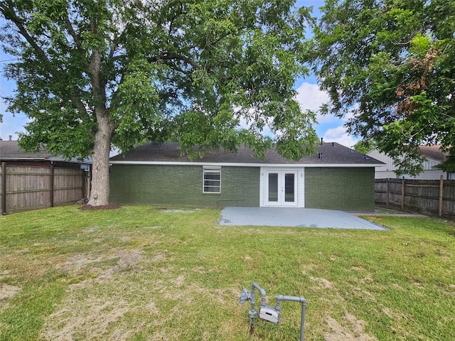 back of property with french doors, a lawn, and a patio