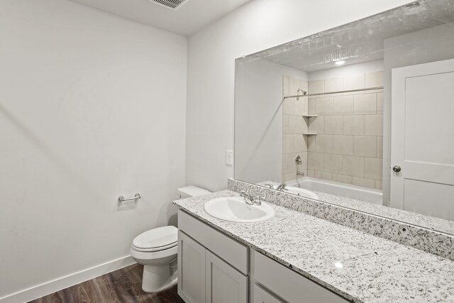 full bathroom featuring wood-type flooring, toilet, vanity, and tiled shower / bath combo