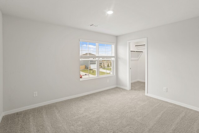 unfurnished bedroom with a closet, a walk in closet, and carpet flooring