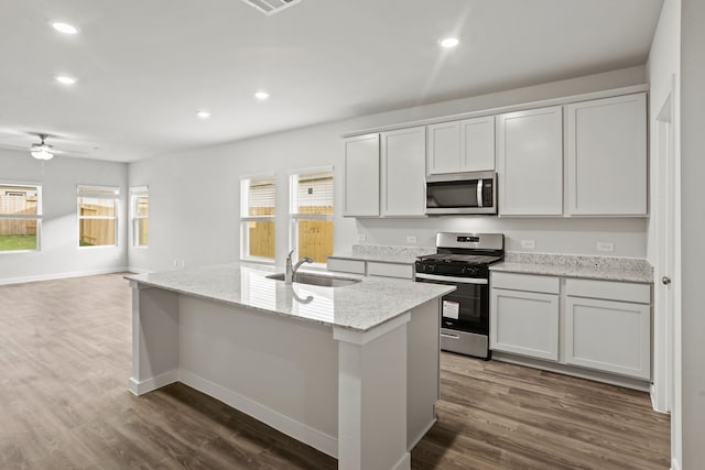 kitchen with sink, white cabinetry, appliances with stainless steel finishes, and a center island with sink