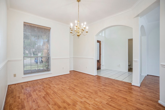 unfurnished room with light wood-type flooring, a chandelier, and crown molding