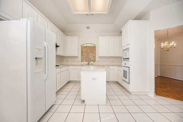 kitchen featuring white cabinets, white appliances, an inviting chandelier, and a kitchen island