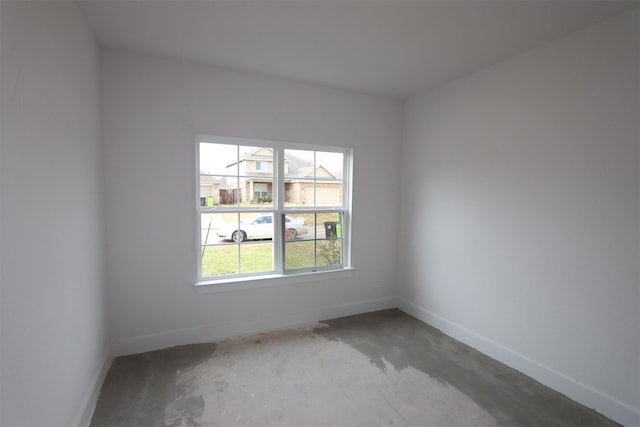 spare room featuring unfinished concrete flooring and baseboards