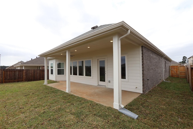 rear view of property featuring a patio, a yard, a fenced backyard, and brick siding