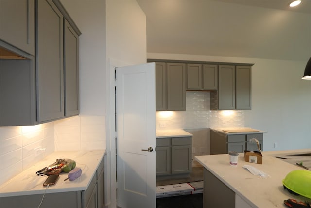 kitchen with light stone counters, decorative backsplash, and gray cabinets