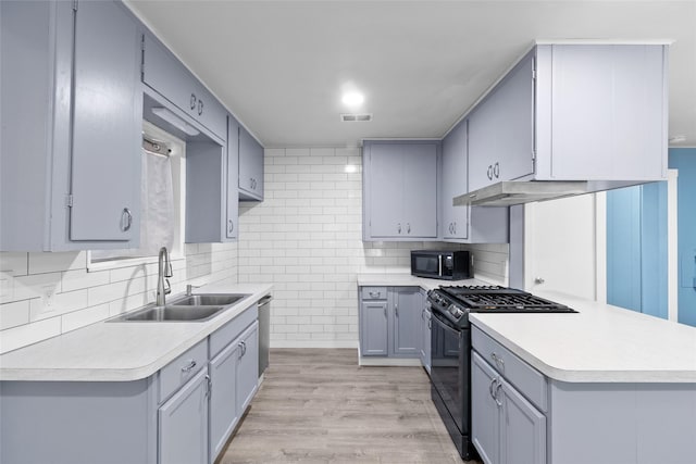 kitchen featuring black appliances, backsplash, sink, and light hardwood / wood-style flooring