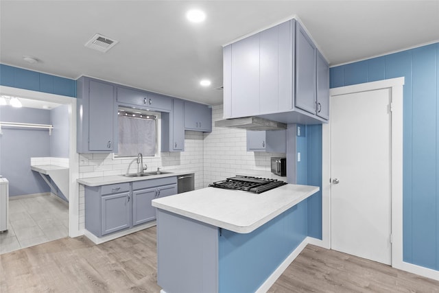 kitchen featuring kitchen peninsula, appliances with stainless steel finishes, a kitchen bar, sink, and light hardwood / wood-style flooring