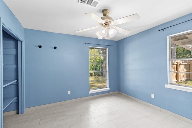 unfurnished room with ceiling fan and a healthy amount of sunlight