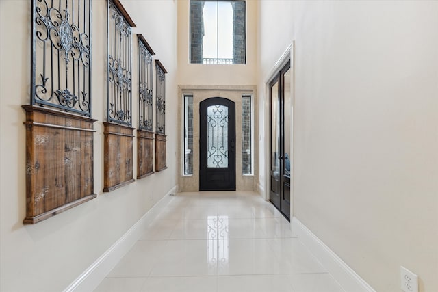 foyer entrance with a towering ceiling and light tile patterned floors