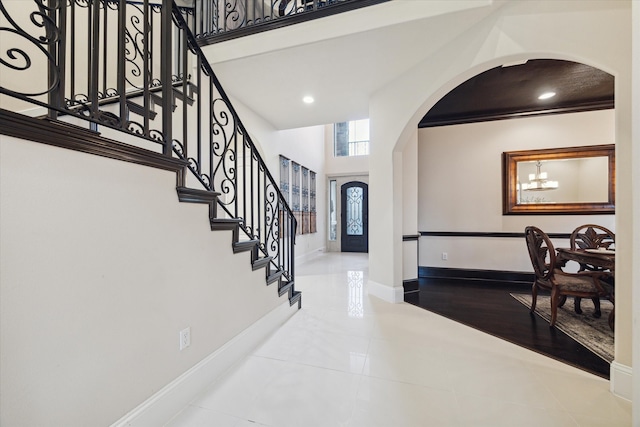 entryway featuring an inviting chandelier, light tile patterned floors, and a high ceiling