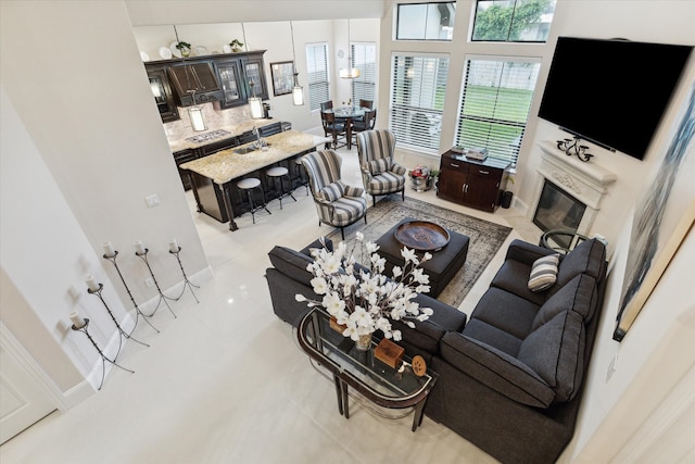 living room featuring a towering ceiling, light tile patterned flooring, and sink