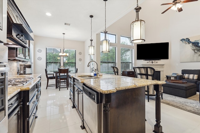 kitchen with appliances with stainless steel finishes, a healthy amount of sunlight, an island with sink, and decorative light fixtures