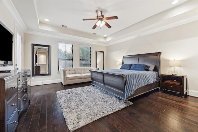 bedroom featuring a raised ceiling, dark wood-type flooring, and ceiling fan