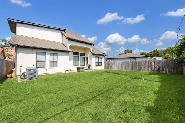 rear view of property with cooling unit and a yard