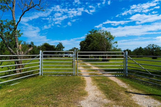 view of gate with a yard and a rural view