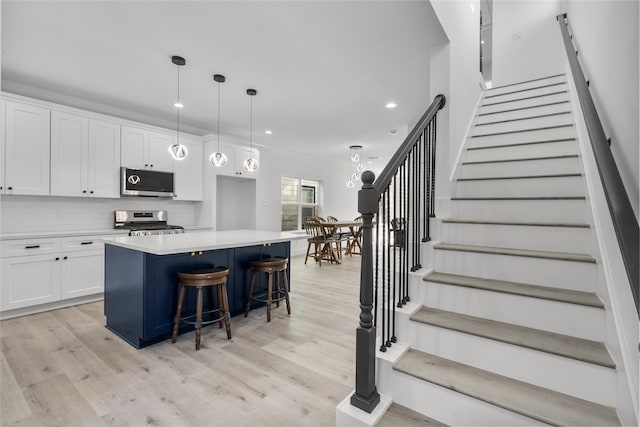 kitchen featuring appliances with stainless steel finishes, white cabinetry, hanging light fixtures, and a kitchen island