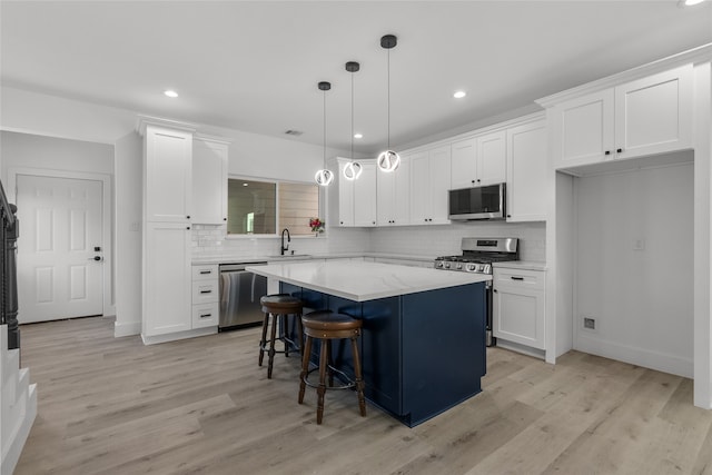 kitchen with stainless steel appliances, sink, a center island, pendant lighting, and light hardwood / wood-style floors