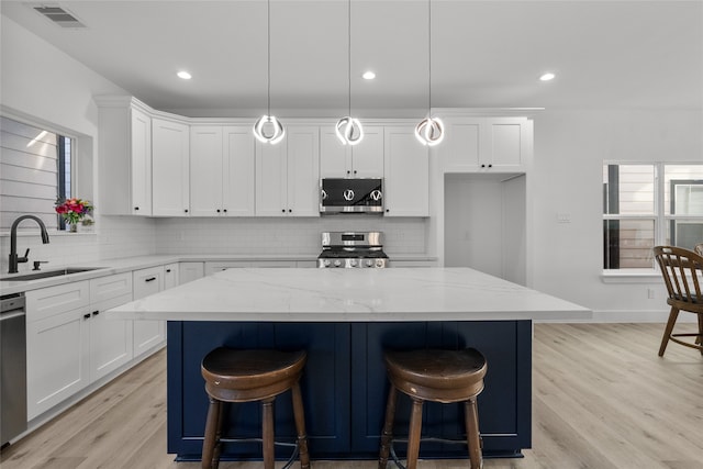 kitchen with a center island, decorative light fixtures, light stone counters, and stainless steel appliances