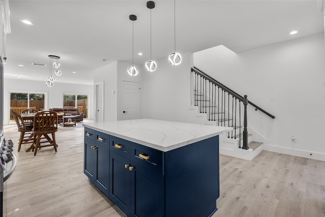 kitchen featuring blue cabinetry, a center island, hanging light fixtures, and light hardwood / wood-style floors