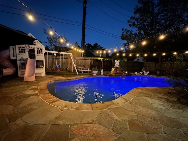 pool at night featuring a patio