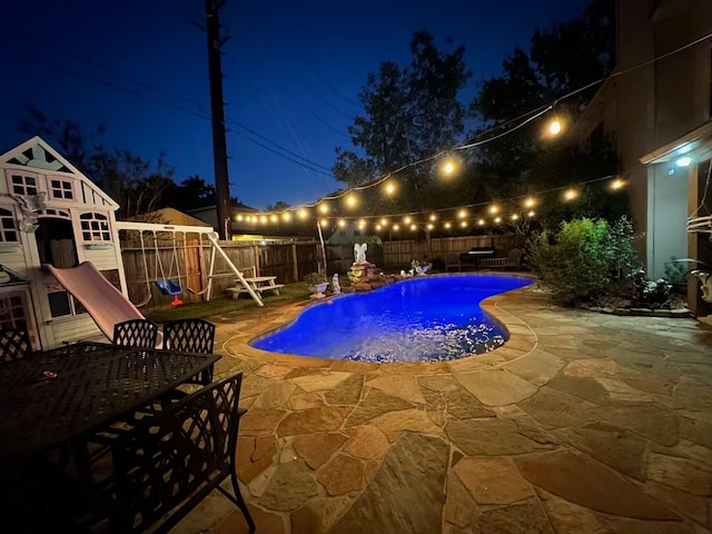 pool at night featuring a patio