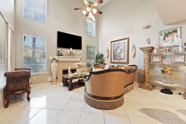 living area with a healthy amount of sunlight, high vaulted ceiling, a tile fireplace, and ceiling fan