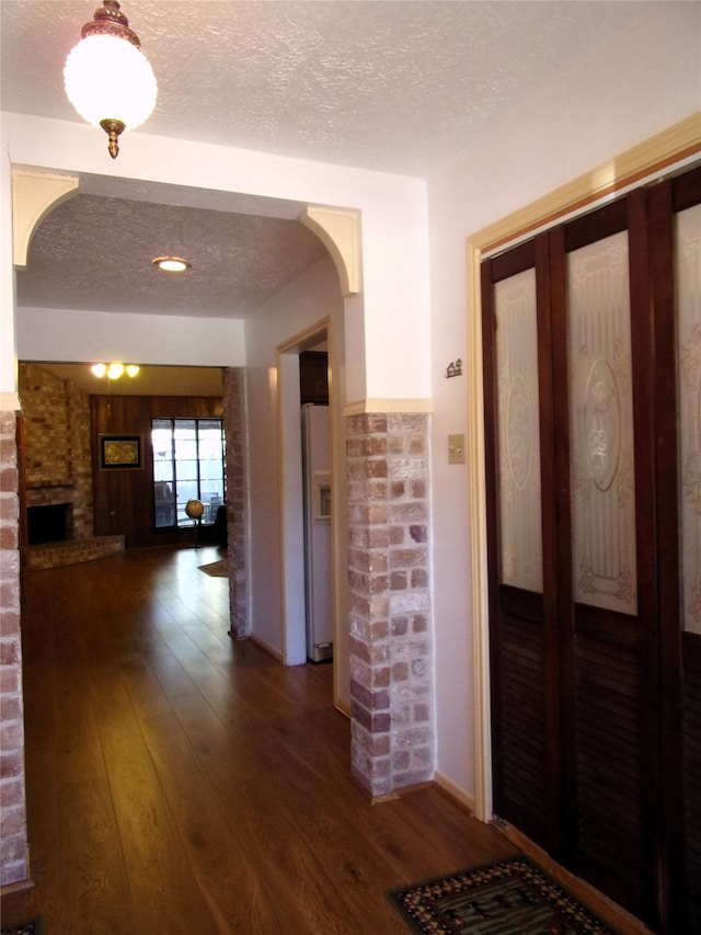 hall with a textured ceiling and dark hardwood / wood-style flooring