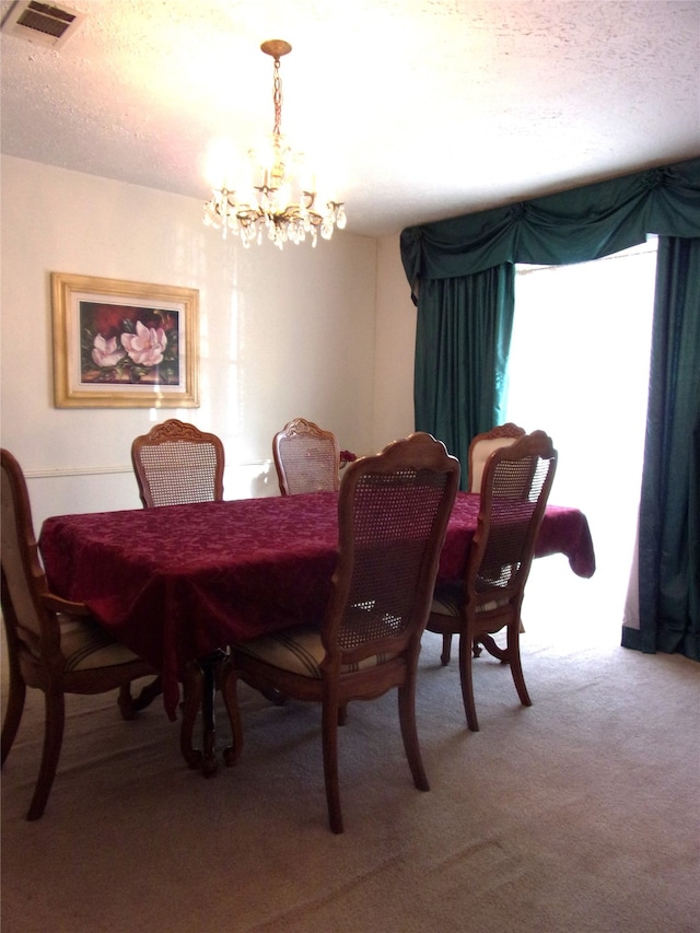 dining area with a chandelier, a textured ceiling, and carpet floors