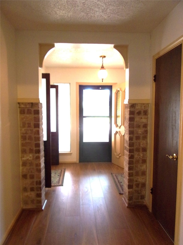 doorway with a textured ceiling and dark hardwood / wood-style floors